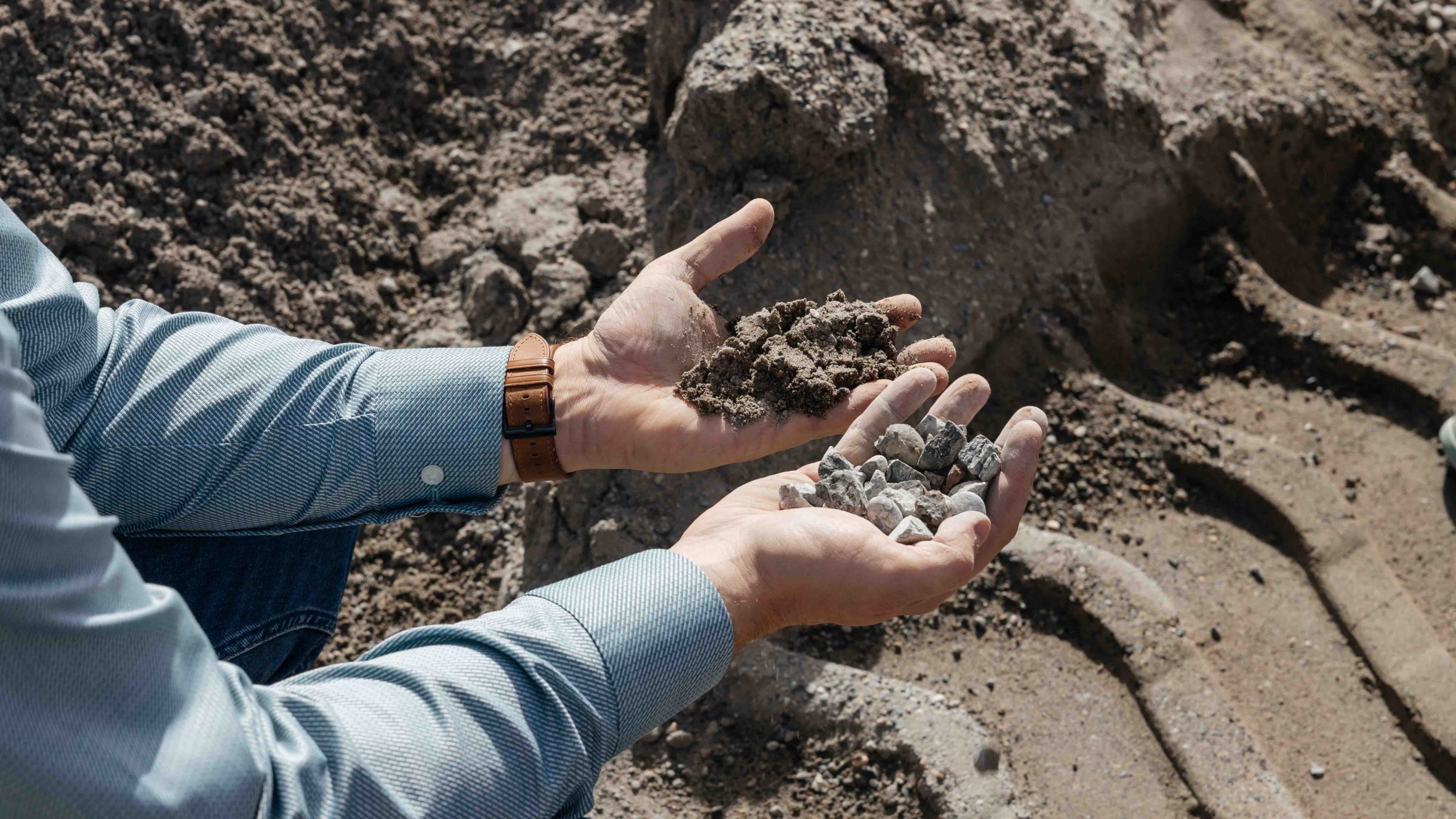 A person holds sand and gravel in their hands, symbolising efficient use of materials in concrete production.
