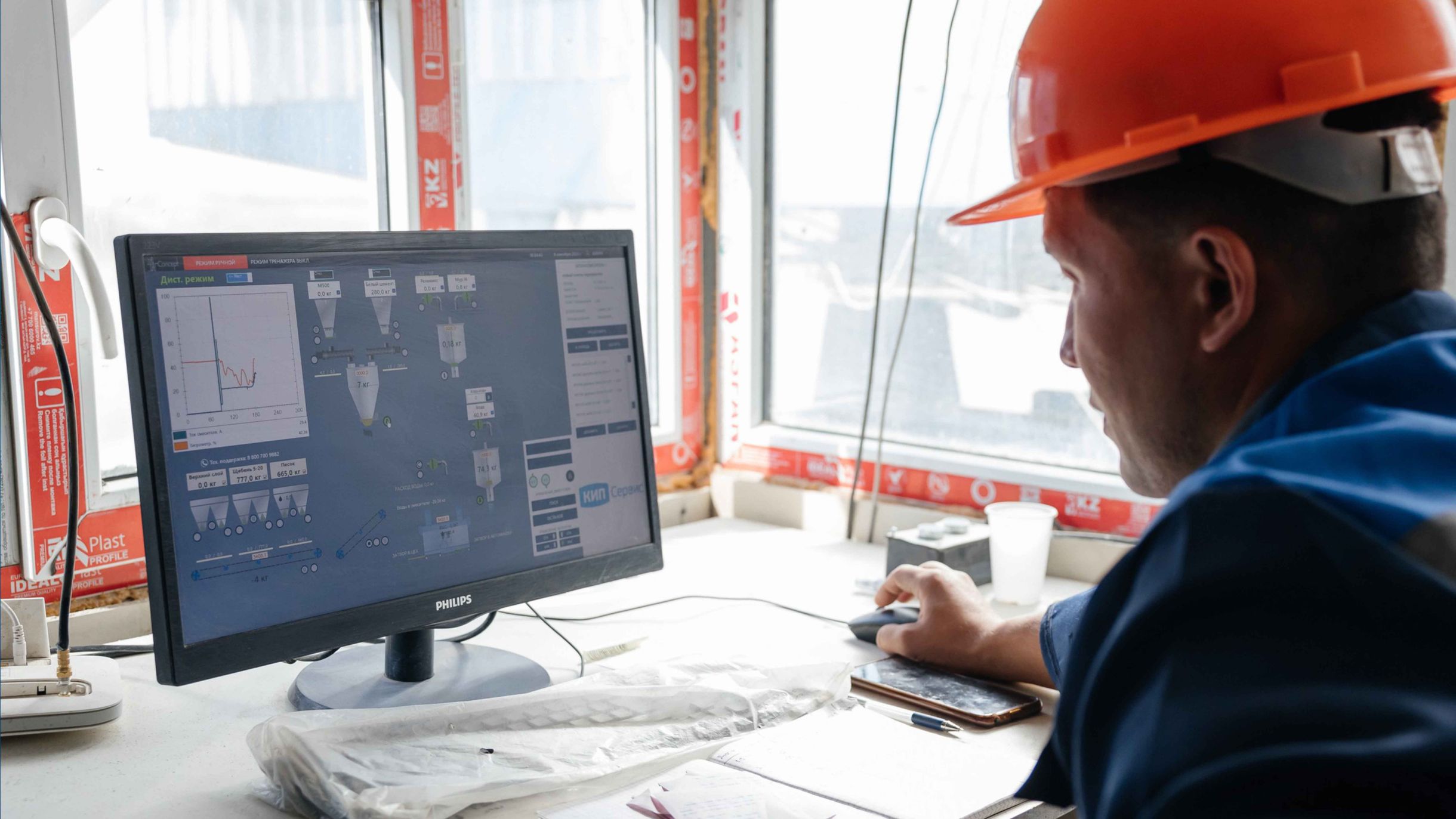 Operator monitors production data of an automated concrete plant on a computer screen.