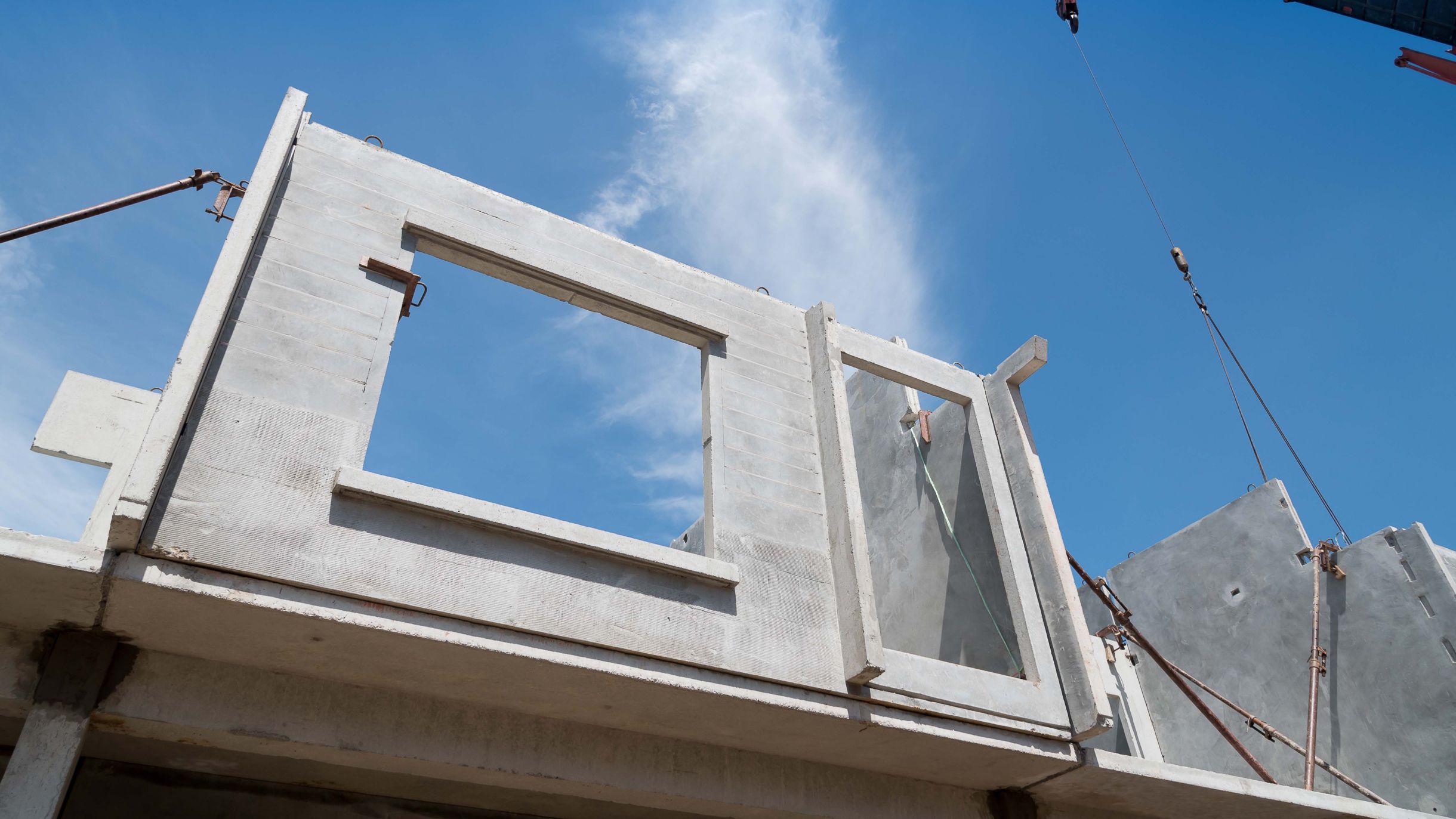 Precast concrete wall element with window openings being installed on site, illustrating efficient and precise prefabricated construction.