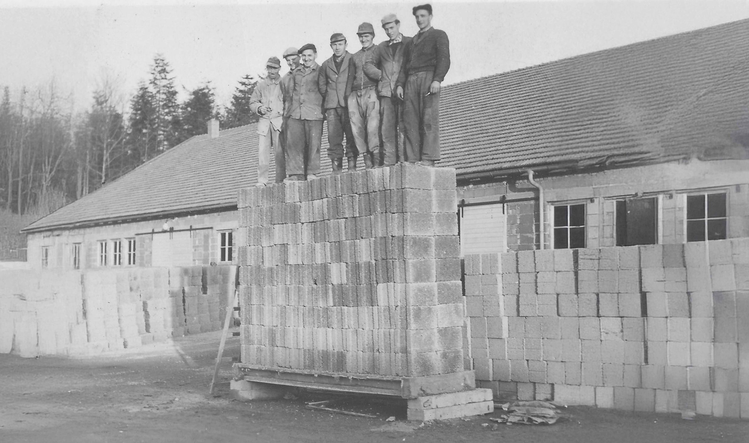 Black-and-white photo from 1964: several men stand on a tall stack of concrete blocks during a hollowcore load test at Weiler GmbH.
